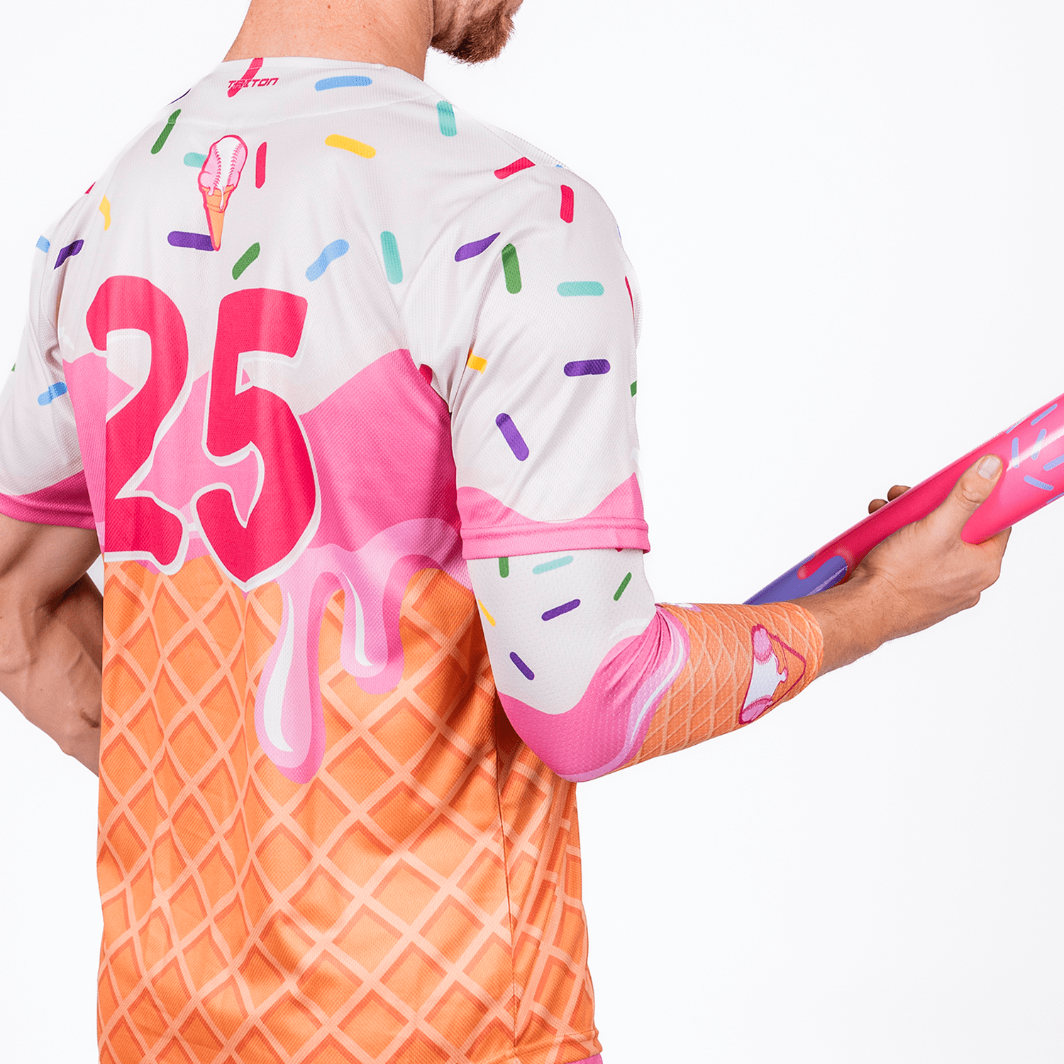 Person wearing a colorful ice cream-themed shirt with the number 25, holding a pink object.