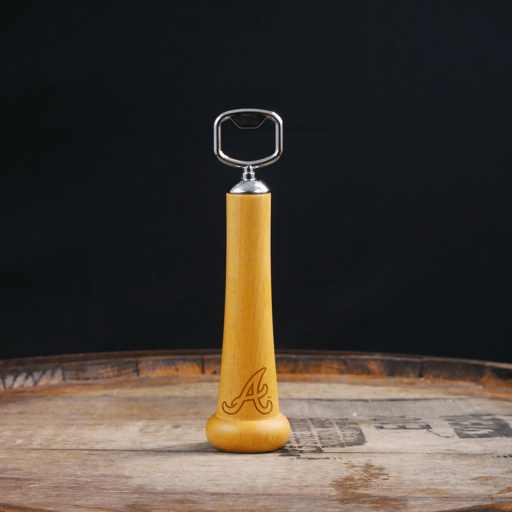 Wooden bottle opener with metal cap on a wooden surface and dark background