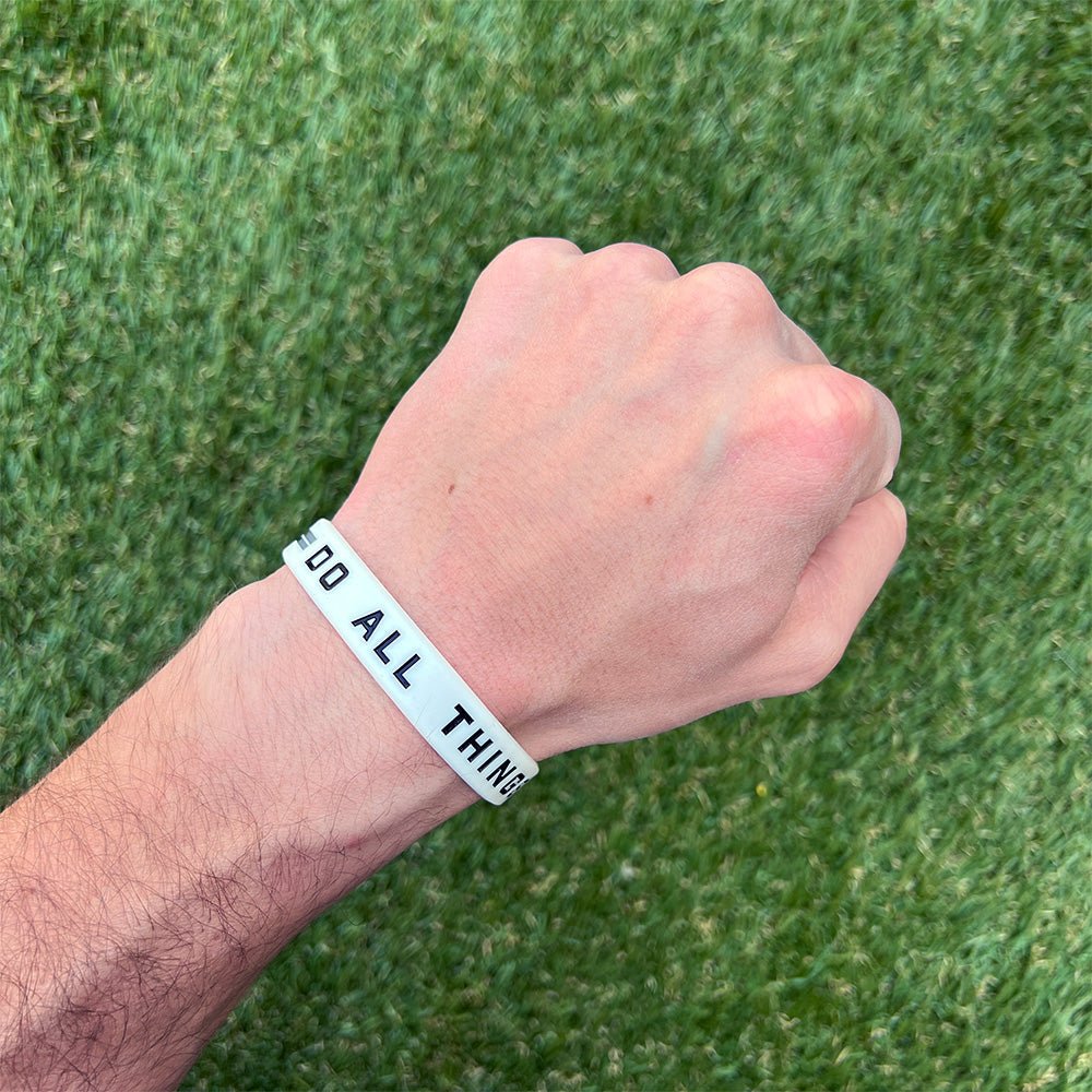 Hand wearing a wristband with text on a grass background