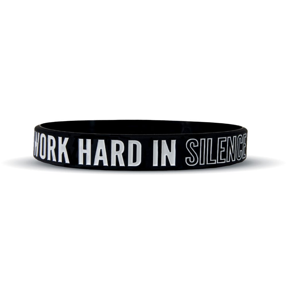 Black wristband with white text 'WORK HARD IN SILENCE' on a white background