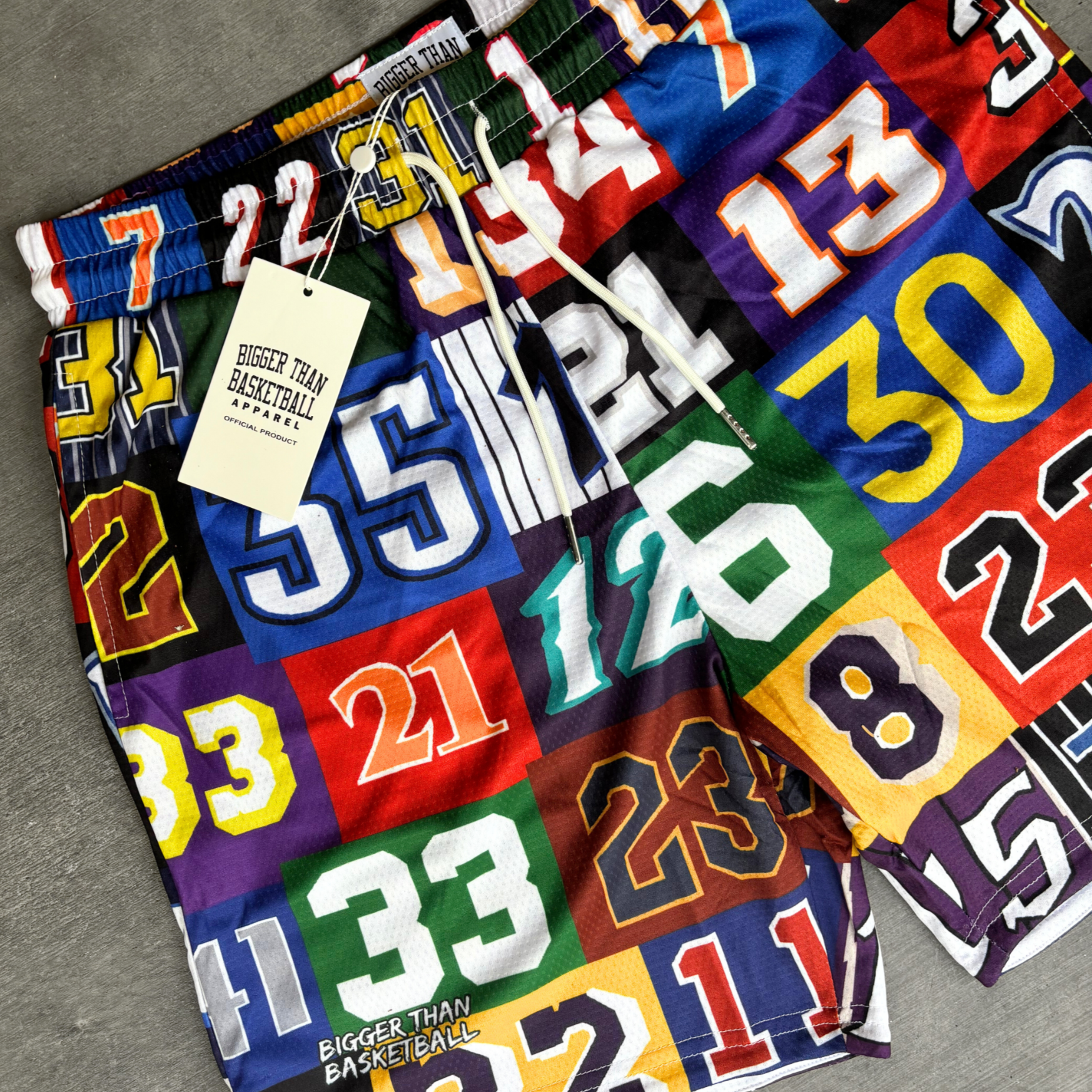 Collection of Colorful fabric with numbers and a 'Bigger Than Basketball' tag on a gray surface in a gallery layout
