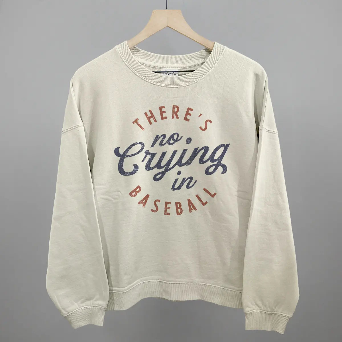 Beige sweatshirt with 'There's no crying in baseball' text on a gray background