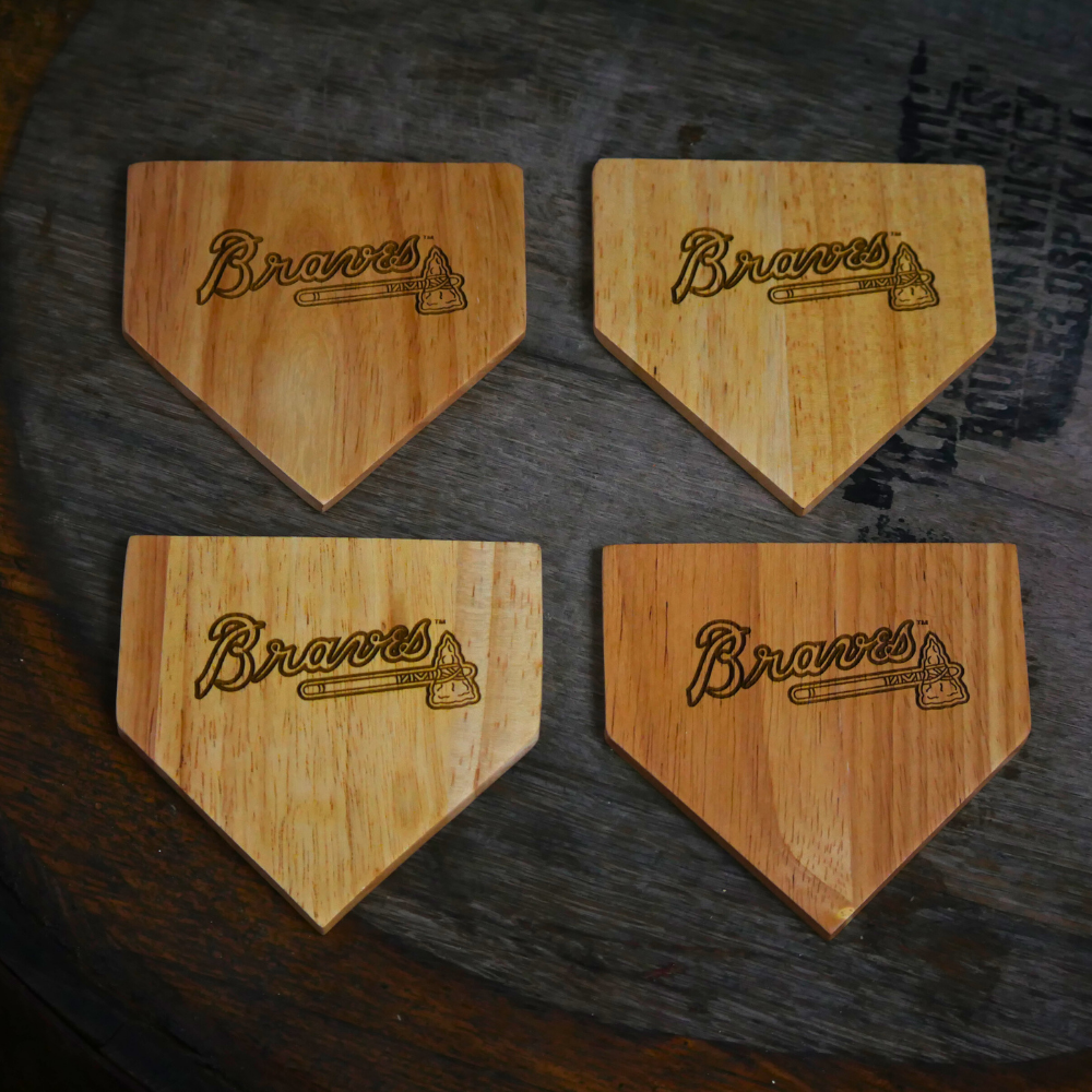 Collection of Four wooden home plate-shaped coasters with 'Braves' branding on a dark surface. in a gallery layout