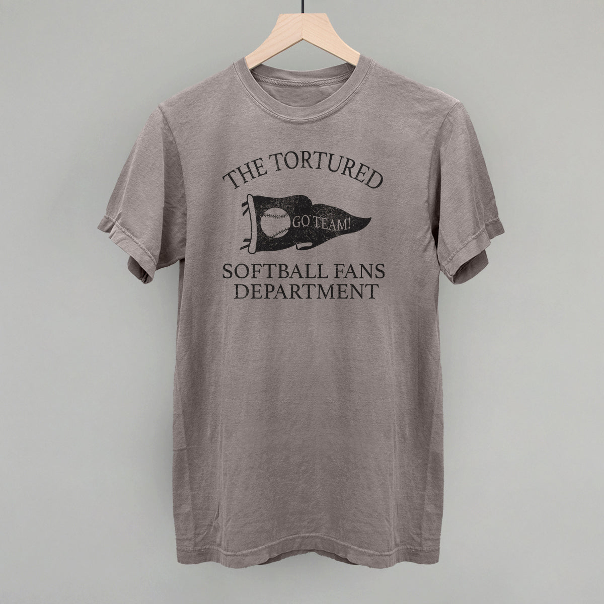Gray t-shirt with 'The Tortured Softball Fans Department' text and graphic on a hanger against a gray background