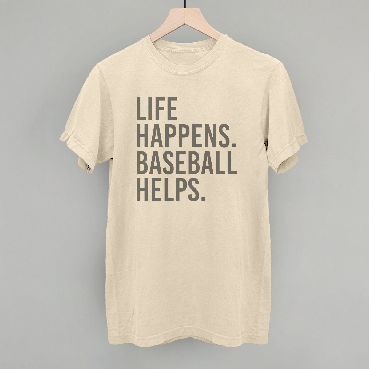 Beige t-shirt with 'Life happens. Baseball helps.' text on a gray background