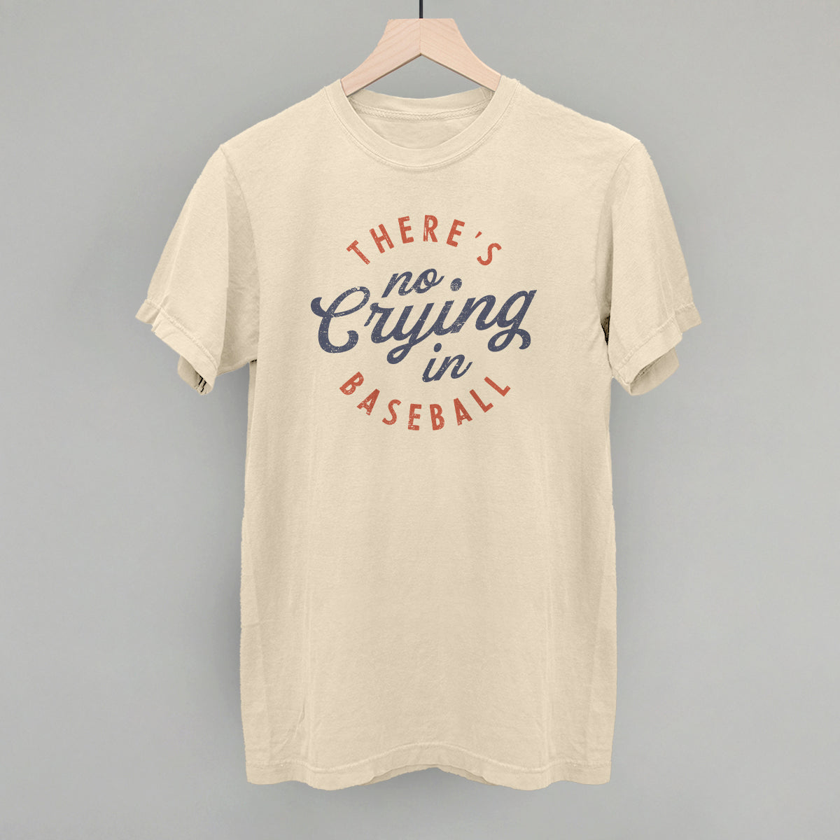 Collection of Beige t-shirt with 'There's no crying in baseball' text on a gray background in a gallery layout