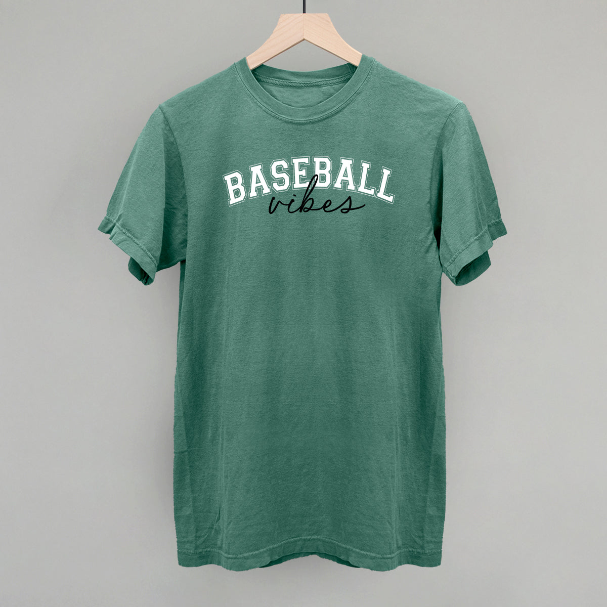 Collection of Green t-shirt with 'BASEBALL vibes' text on a wooden hanger against a gray background in a gallery layout