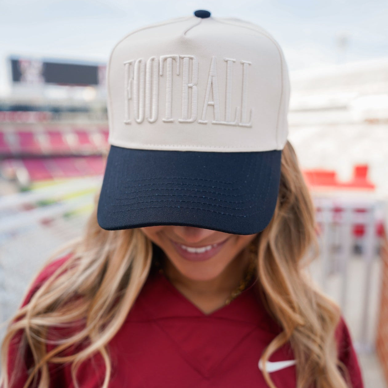 Person wearing a cap with 'FOOTBALL' and a red 'ARKANSAS' shirt in an outdoor setting.