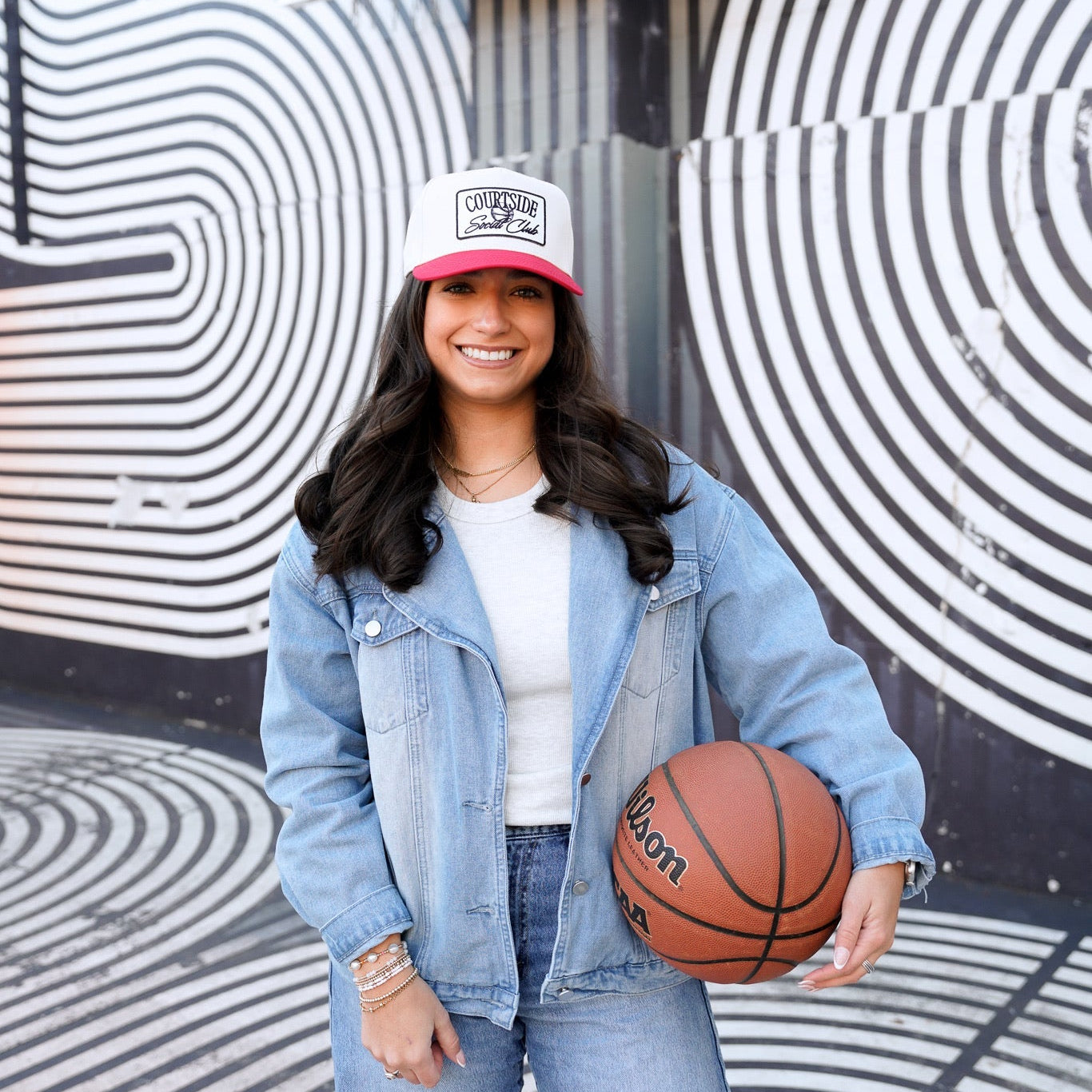 Person holding a basketball in front of a mural with concentric circles