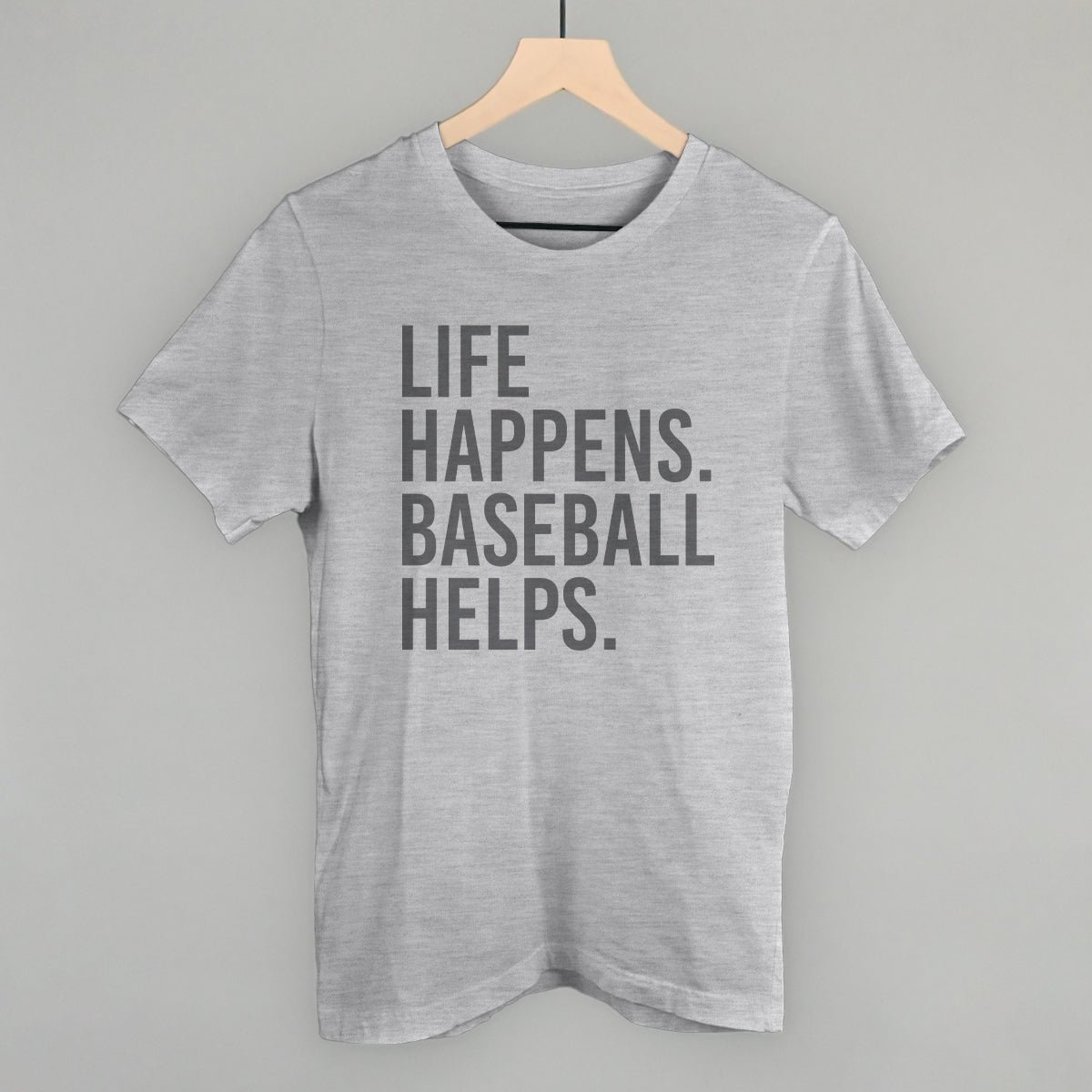 Collection of Gray t-shirt with 'Life happens. Baseball helps.' text on a hanger against a gray background in a gallery layout