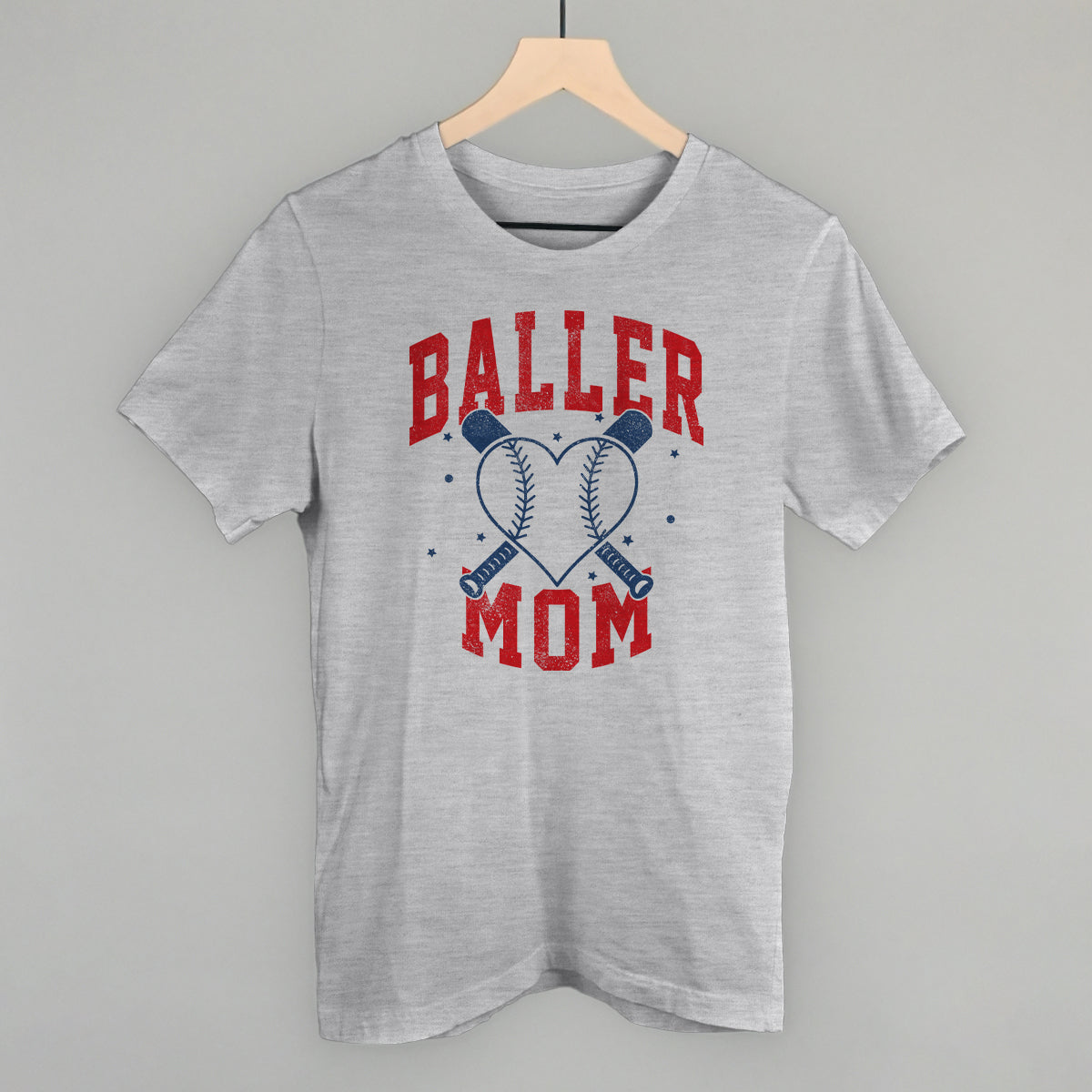 Gray t-shirt with 'Baller Mom' text and graphic on a hanger against a gray background