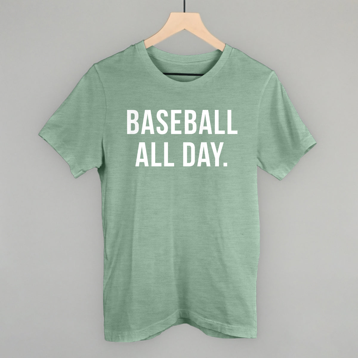 Green t-shirt with 'BASEBALL ALL DAY.' text on a hanger against a gray background