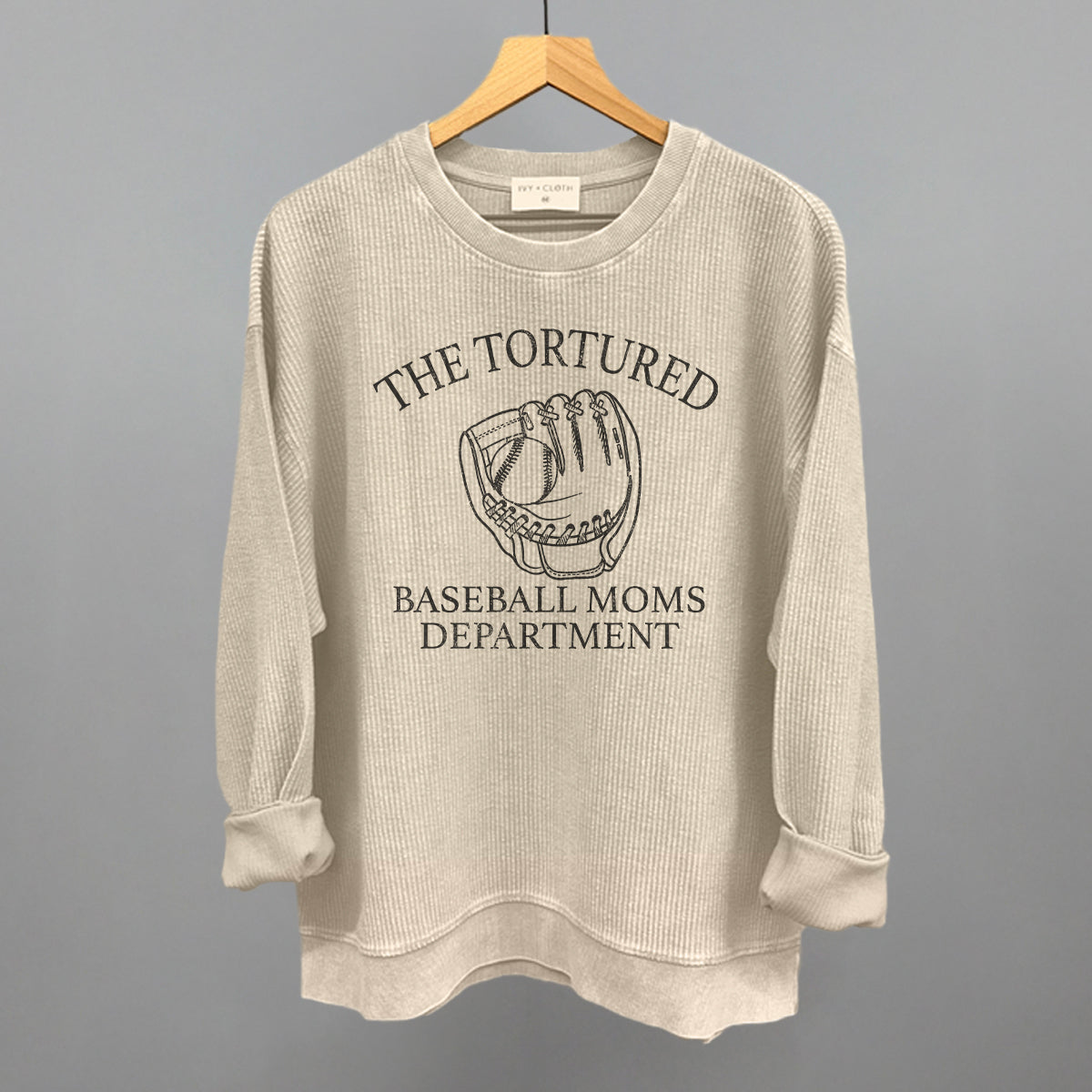 Beige sweatshirt with graphic and text on a hanger against a gray background