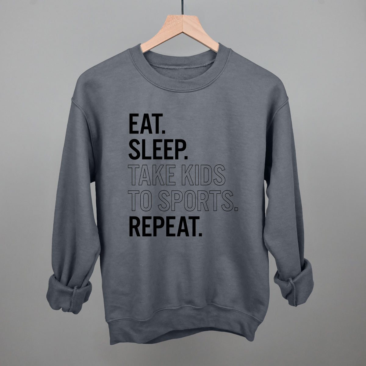 Collection of charcoal comfort colors sweatshirt with text 'EAT. SLEEP. TAKE KIDS TO SPORTS. REPEAT.' on a gray background in a gallery layout