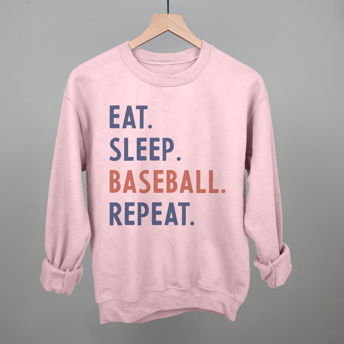 Collection of Pink sweatshirt with 'Eat. Sleep. Baseball. Repeat.' text on a hanger against a gray background in a gallery layout