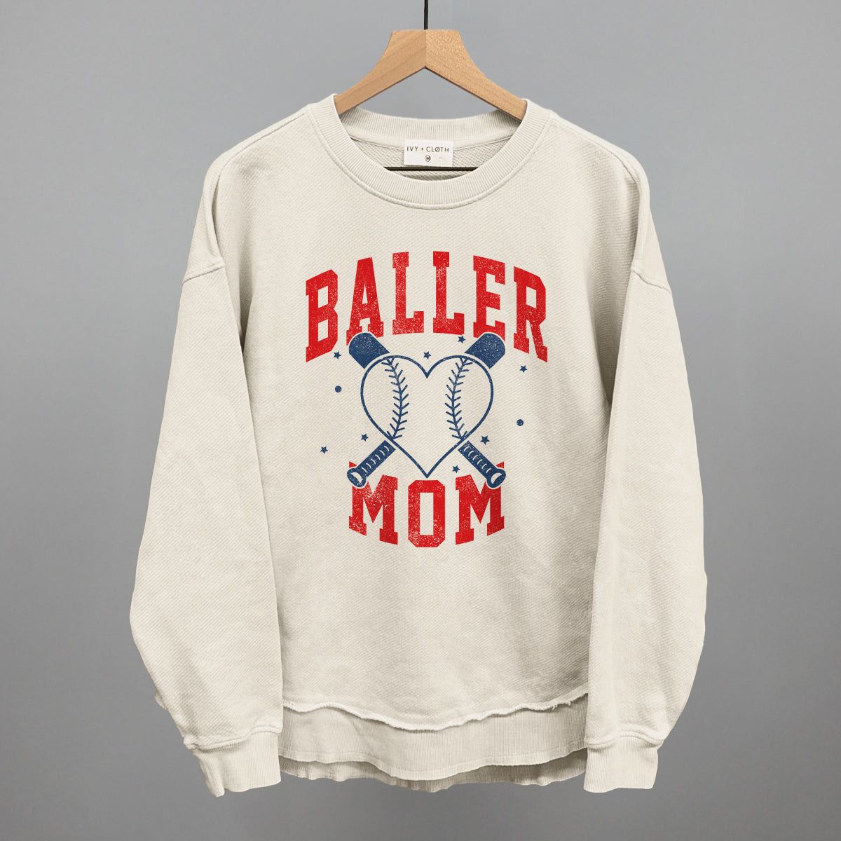 Beige sweatshirt with 'Baller Mom' text and baseball graphics on a gray background