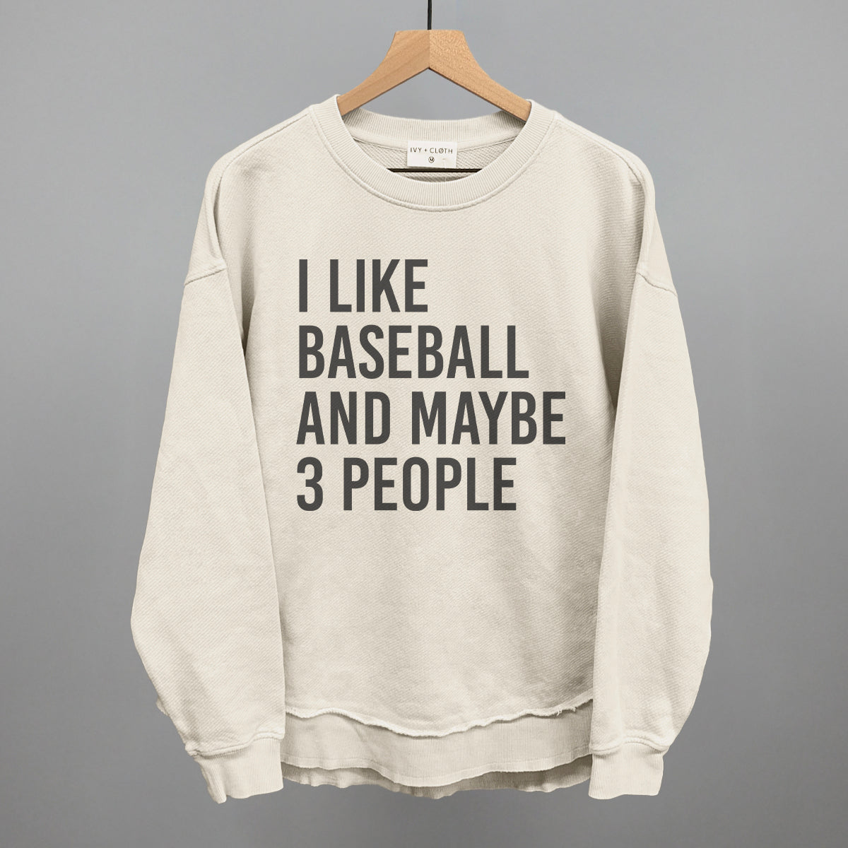 Tapioca sweatshirt with text 'I like baseball and maybe 3 people' on a hanger against a gray background