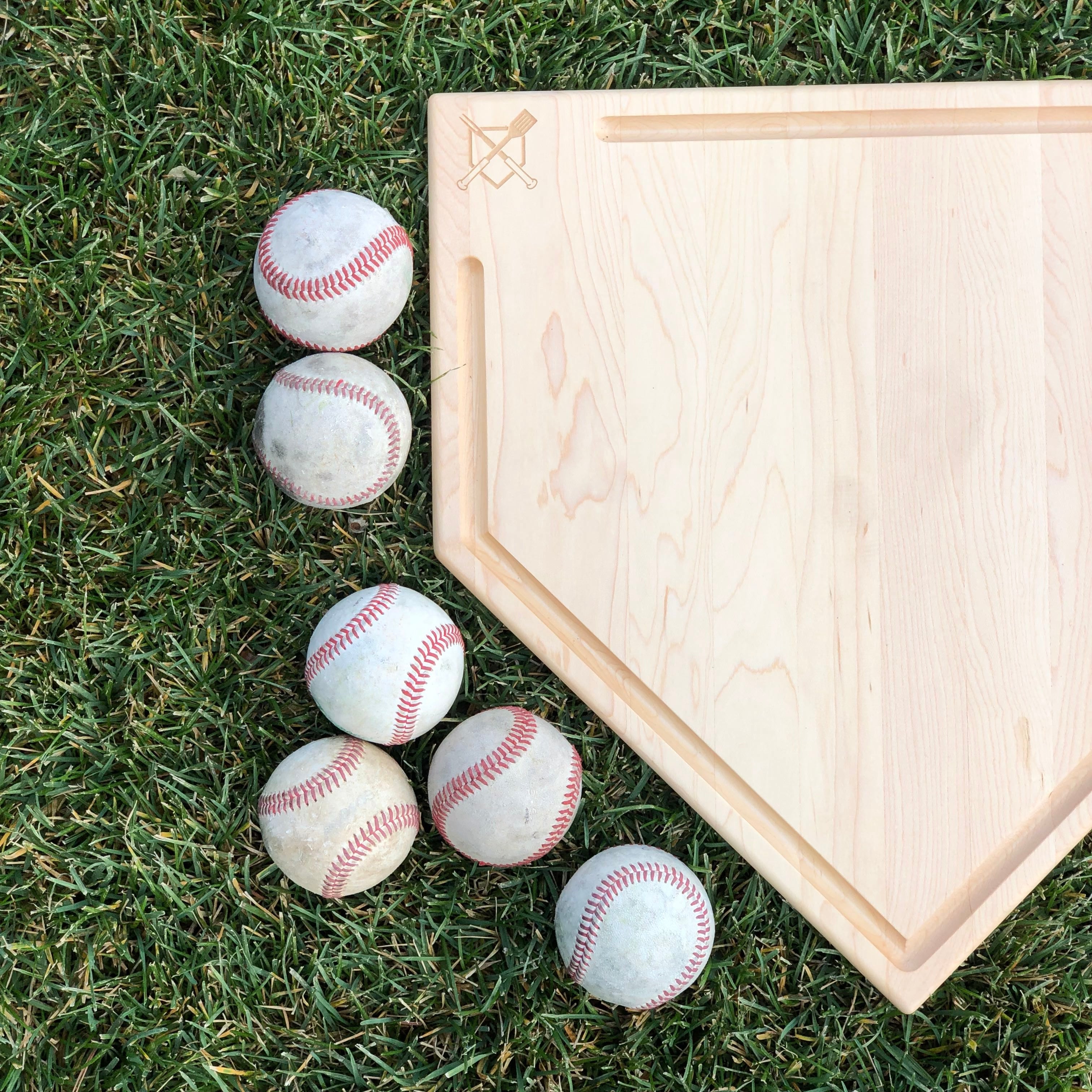 Collection of Baseballs on grass next to a wooden home plate in a gallery layout