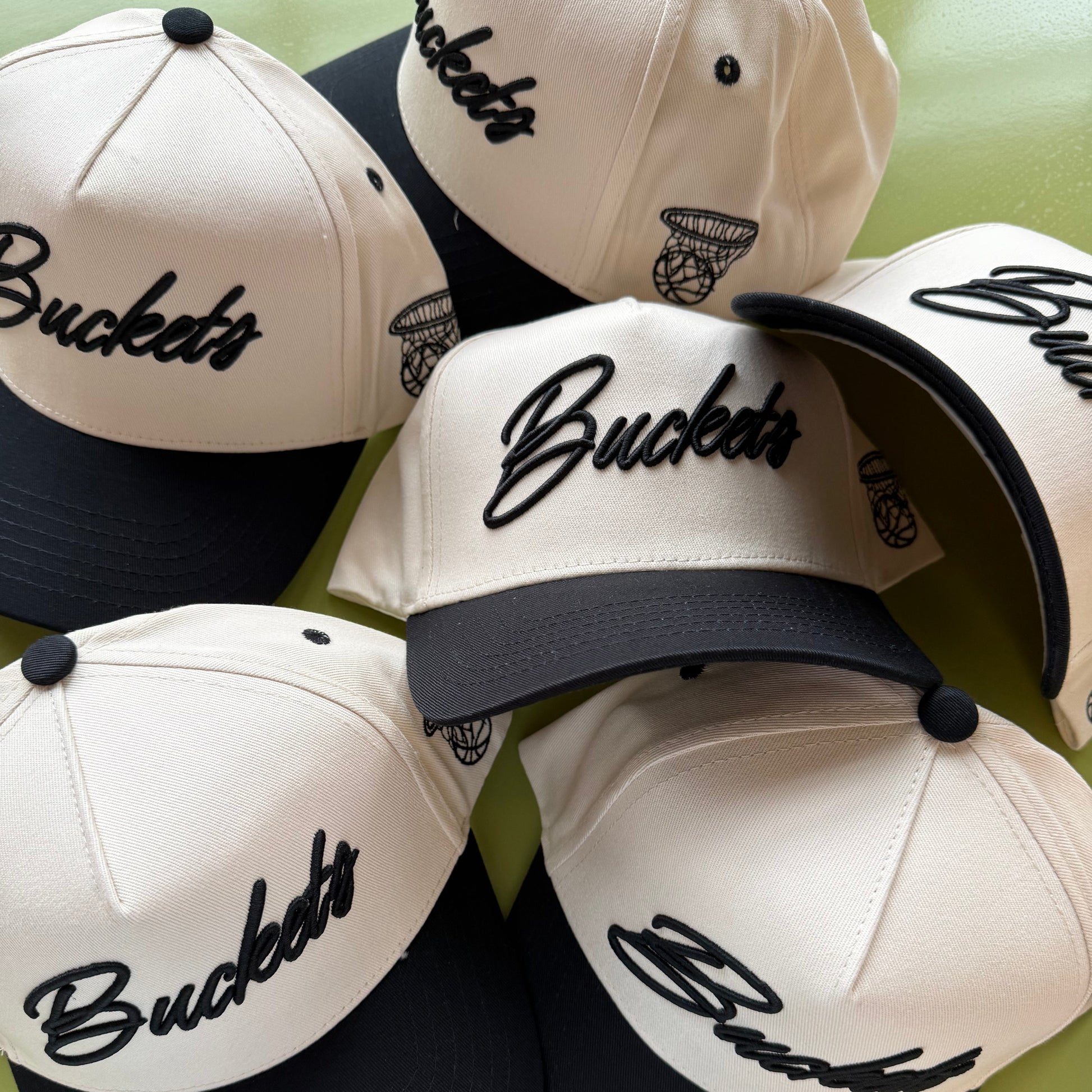 Collection of 'Buckets' branded caps on a green background