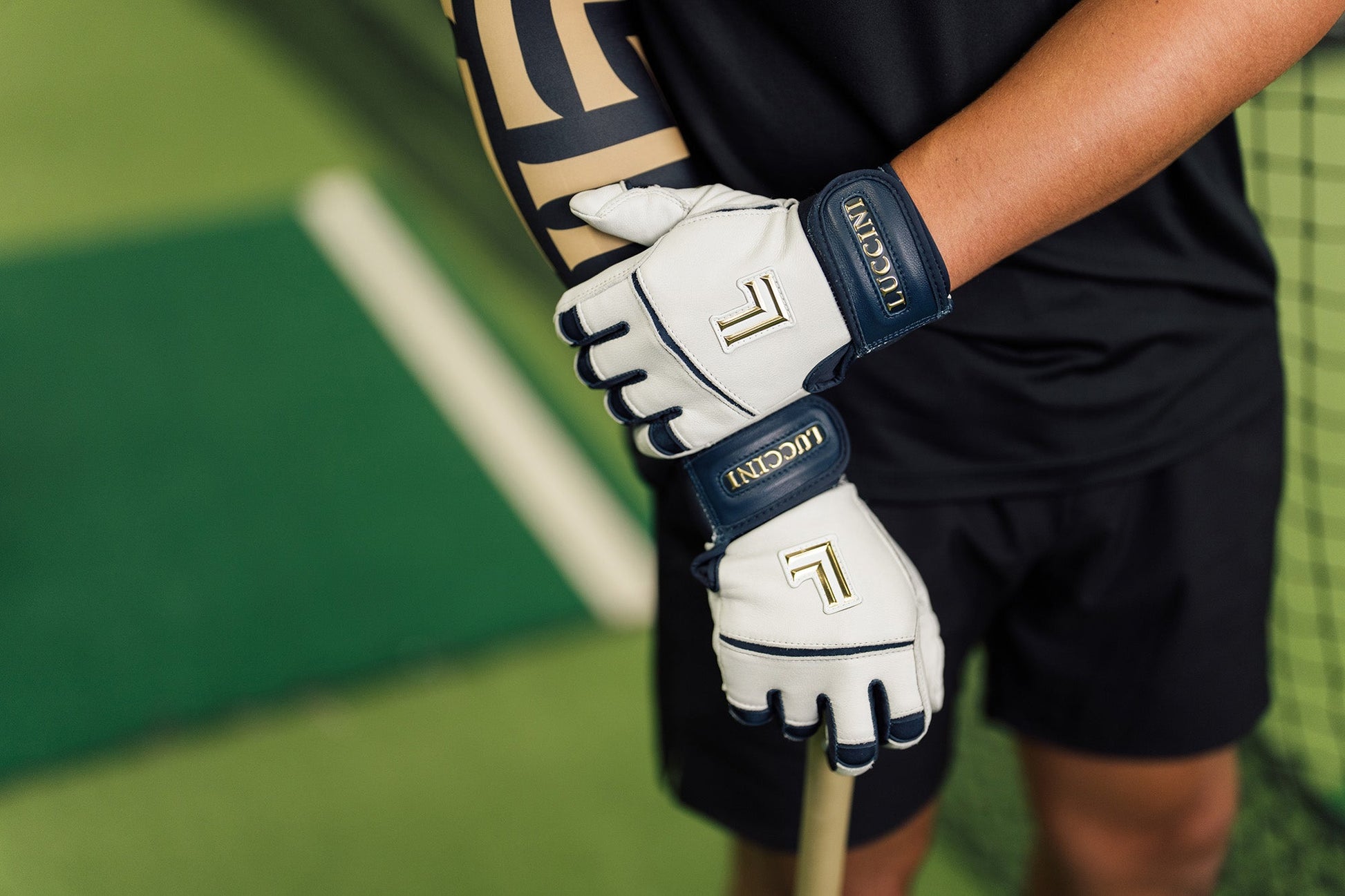 Person holding a baseball ball wearing luccini blue and white batting gloves