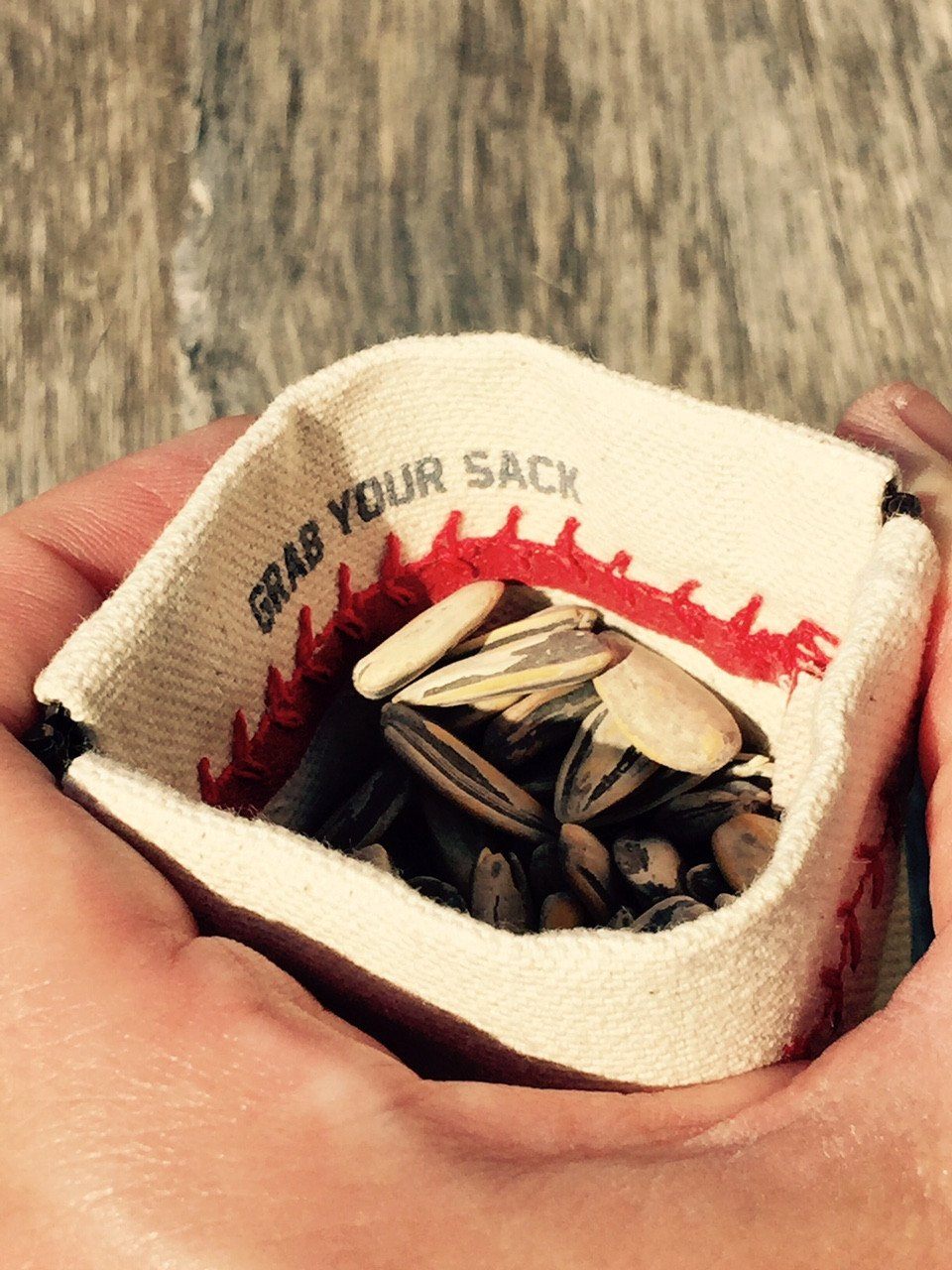 Collection of Small bag filled with seeds held in hands against a wooden background in a gallery layout