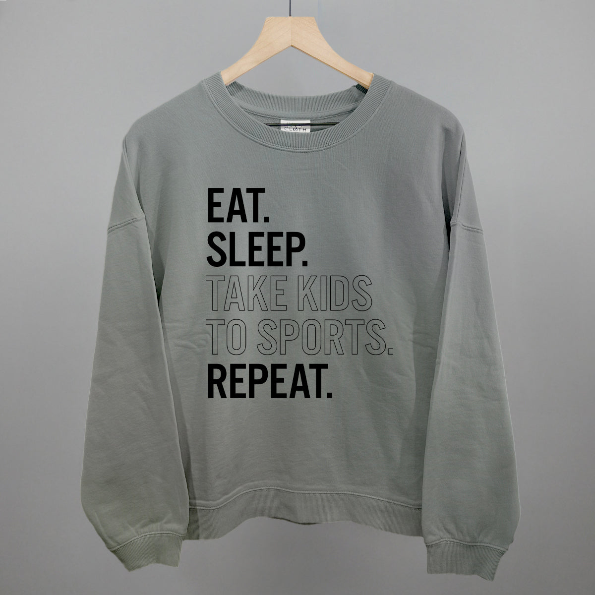Collection of smoke sweatshirt with text 'EAT. SLEEP. TAKE KIDS TO SPORTS. REPEAT.' on a gray background in a gallery layout
