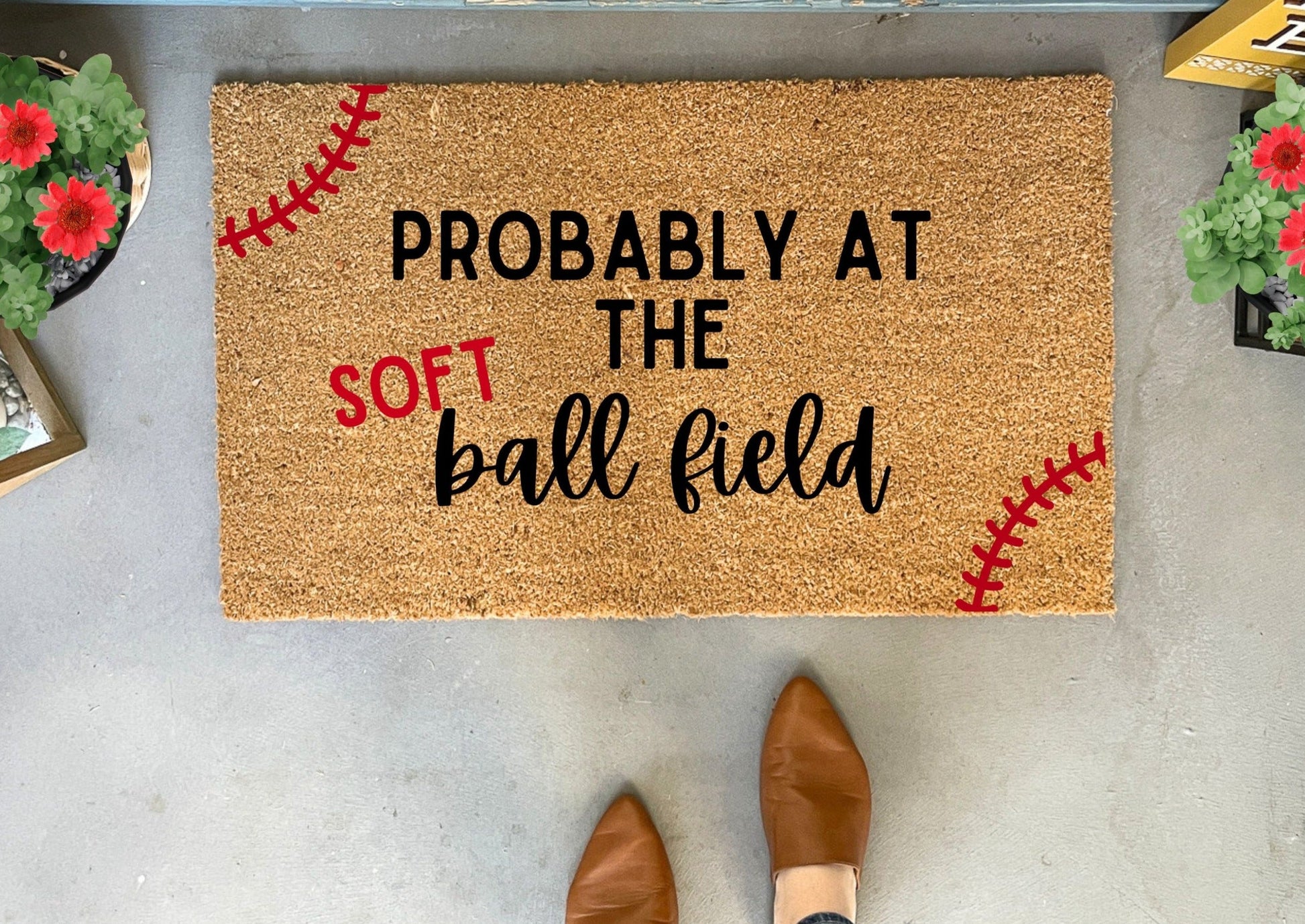 Doormat with text 'Probably at the softball field' on a concrete floor.