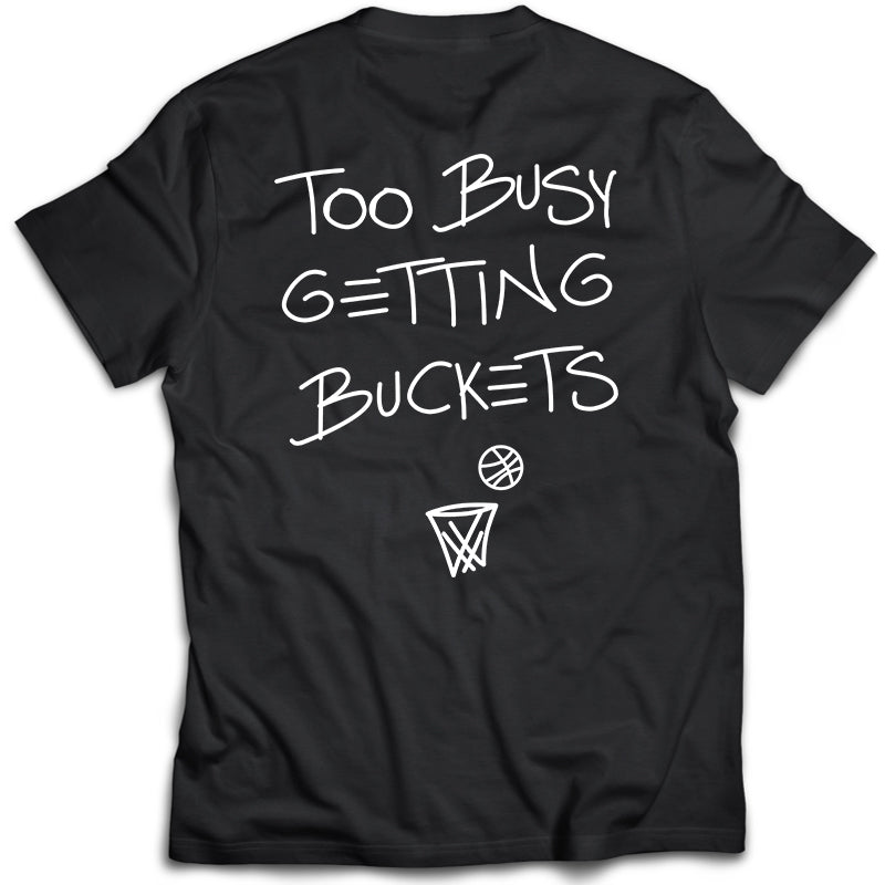 Black t-shirt with 'Too Busy Getting Buckets' text and basketball graphics on a white background