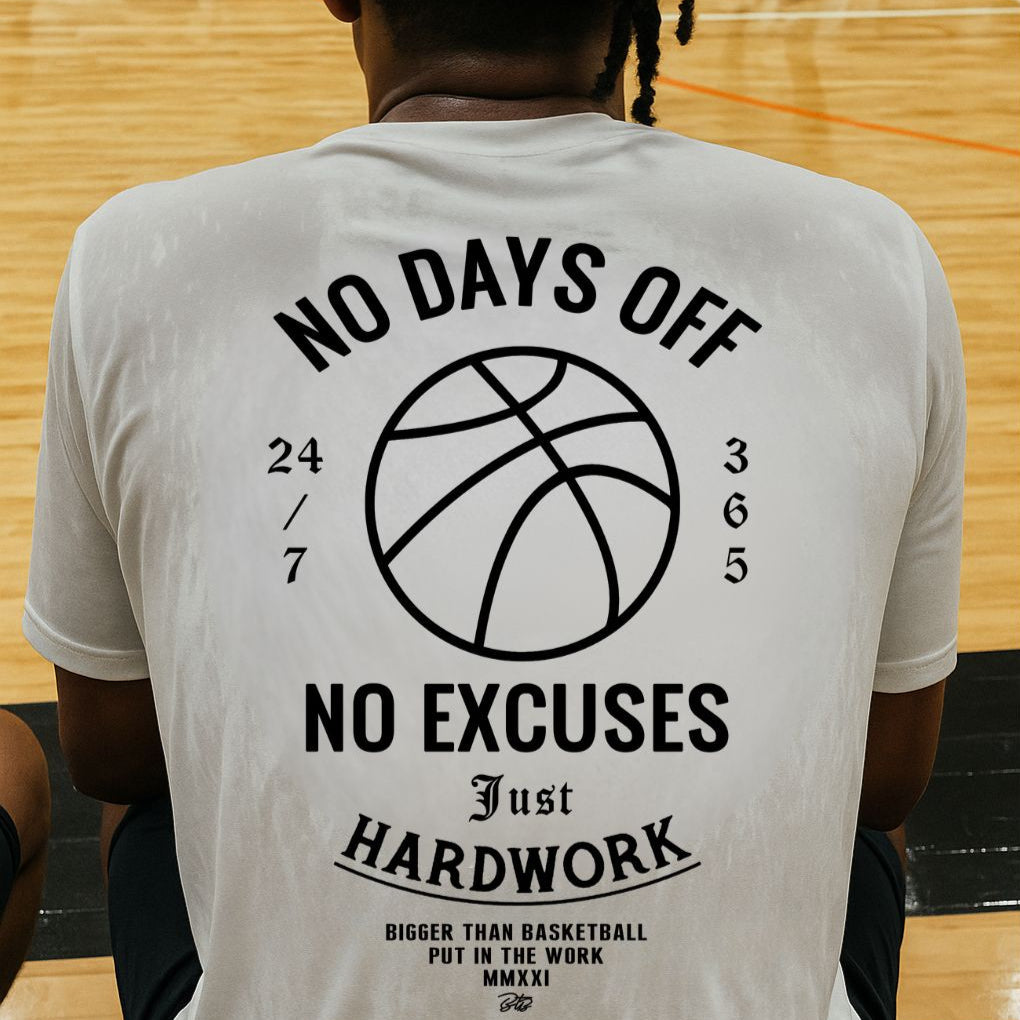 Person wearing a t-shirt with motivational text and a basketball graphic on a gymnasium floor. No days off white t shirt