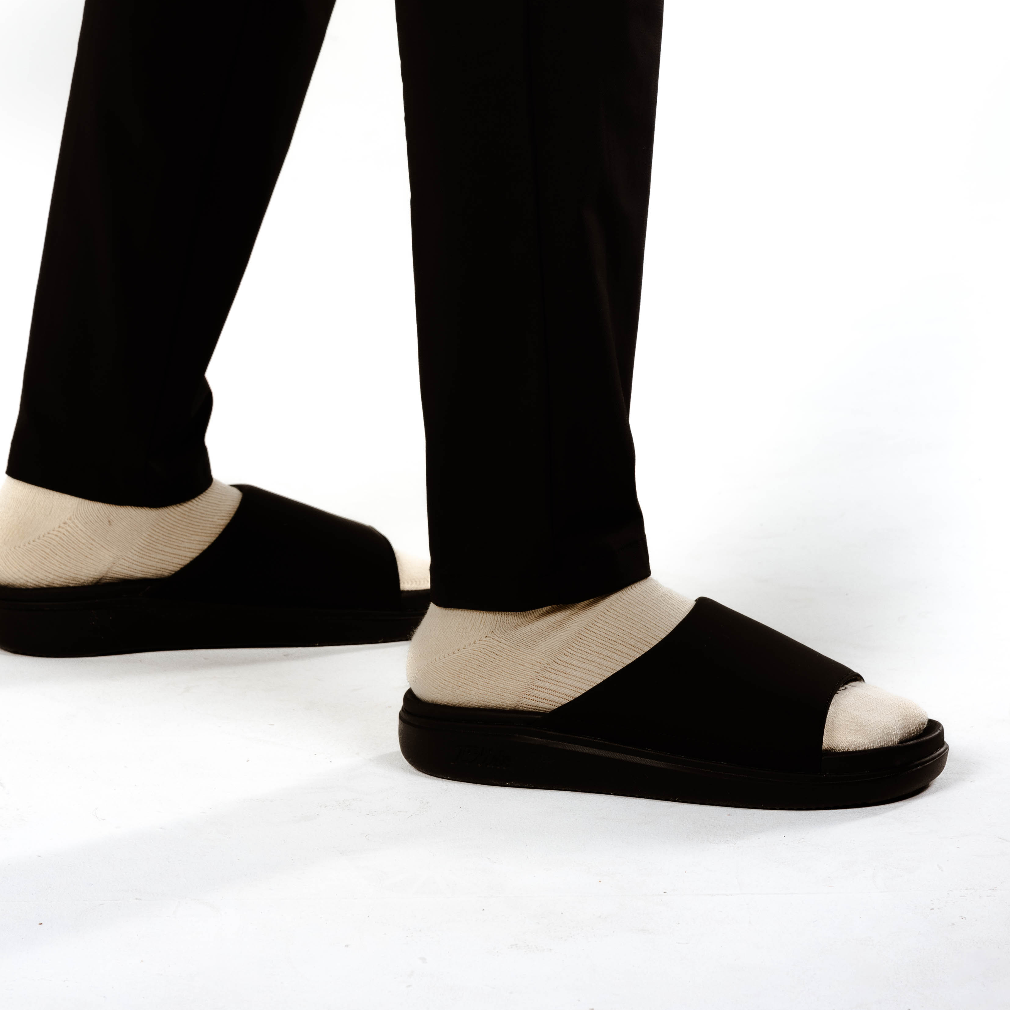 Collection of Black sandals worn with black pants on a white background in a gallery layout