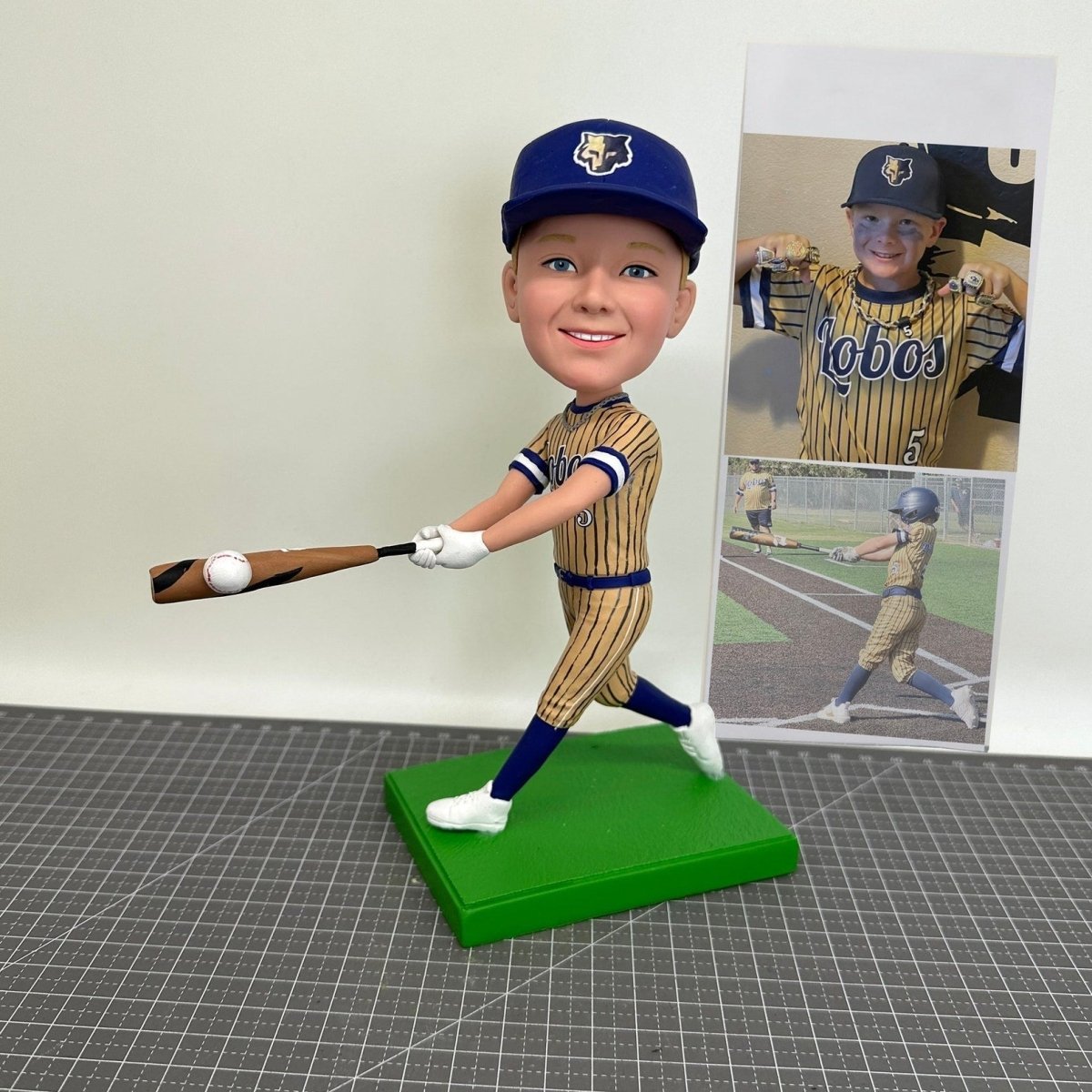 Collection of Bobblehead of a baseball player in uniform with a bat, standing on a green base, with a photo of a real-life player in the background. in a gallery layout