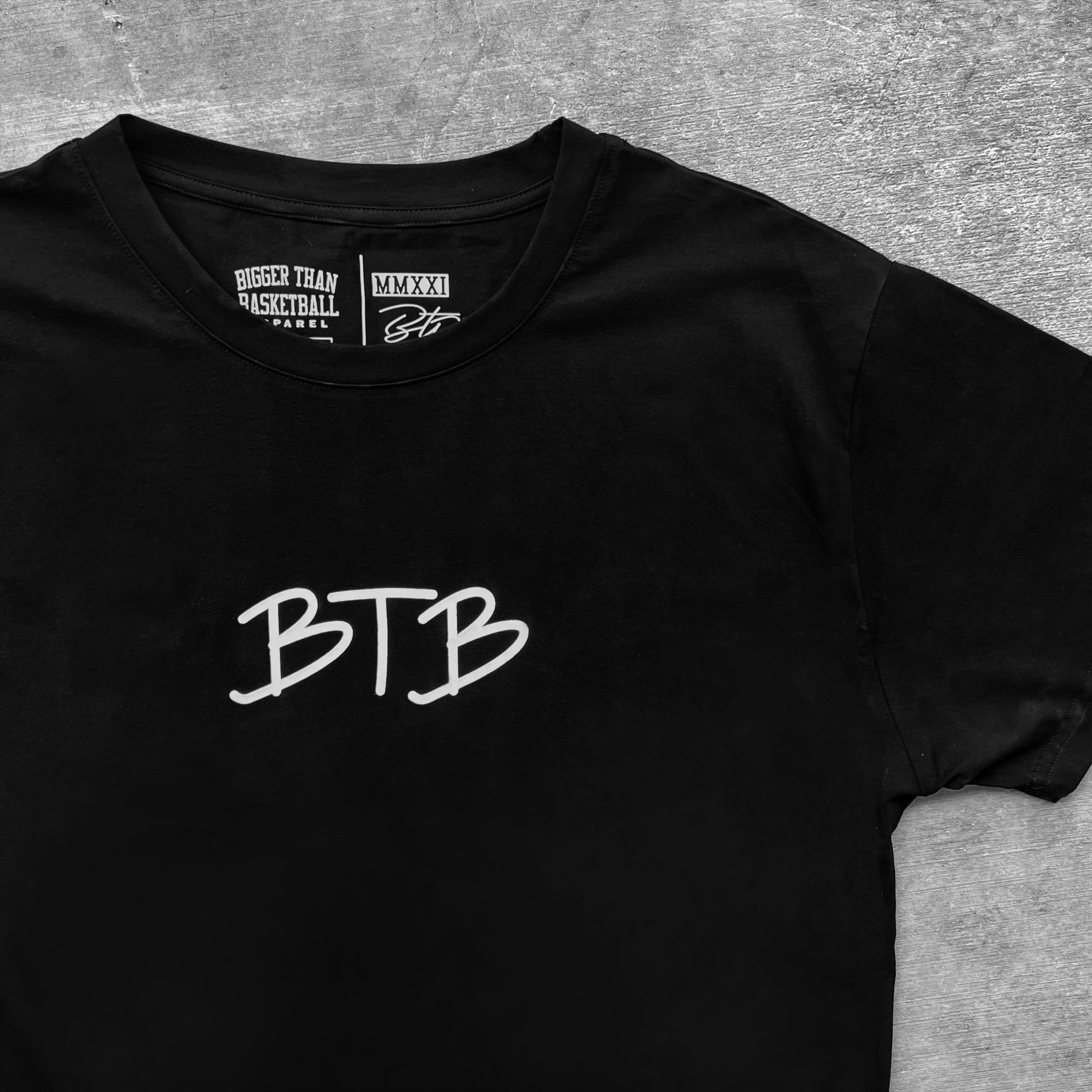 Collection of Black t-shirt with 'BTB' logo on a gray surface. Bigger Than Basketball. in a gallery layout