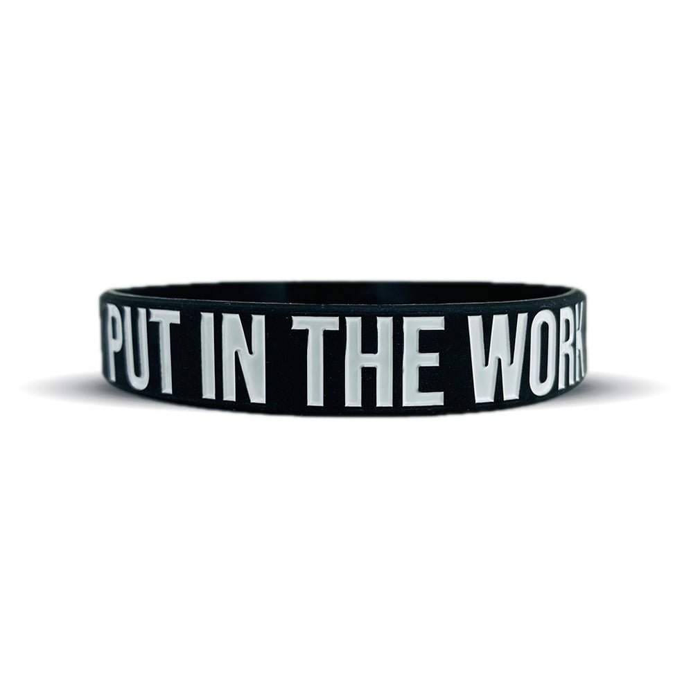 Black wristband with 'PUT IN THE WORK' text on a white background