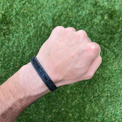 Collection of Hand wearing a black wristband with text on a green grass background in a gallery layout