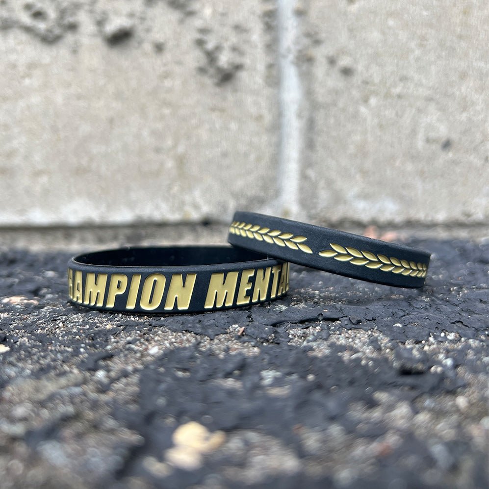 Collection of Black wristbands with gold text on a textured surface in a gallery layout