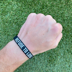 Collection of Hand wearing a black wristband with 'REFUSE TO LOSE' text on a grass background in a gallery layout