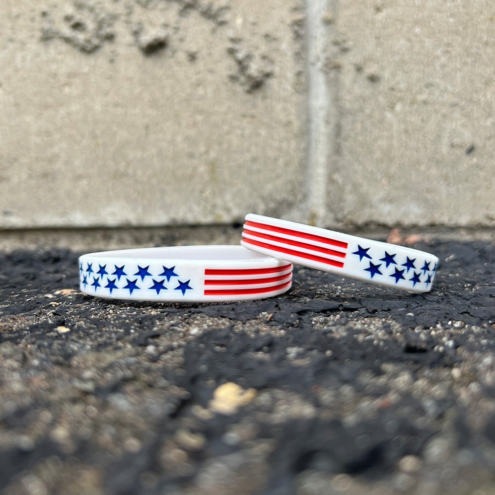 Collection of Two wristbands with American flag design on a concrete surface in a gallery layout