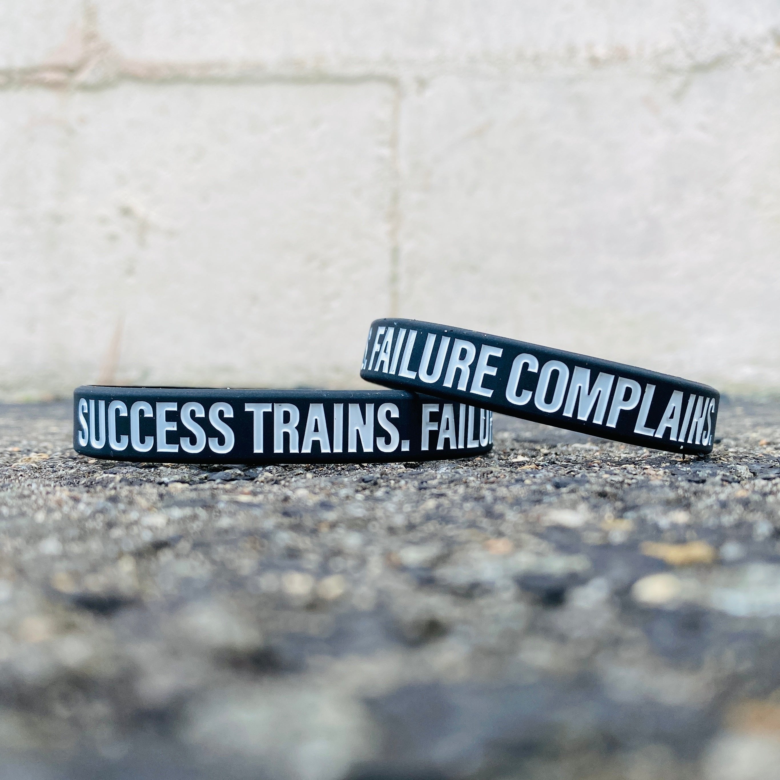 Collection of Black wristbands with motivational text on a textured surface in a gallery layout