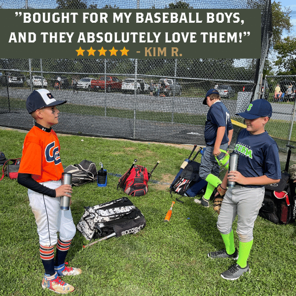 Two young baseball players standing on a field with sports equipment around, holding water bottles.