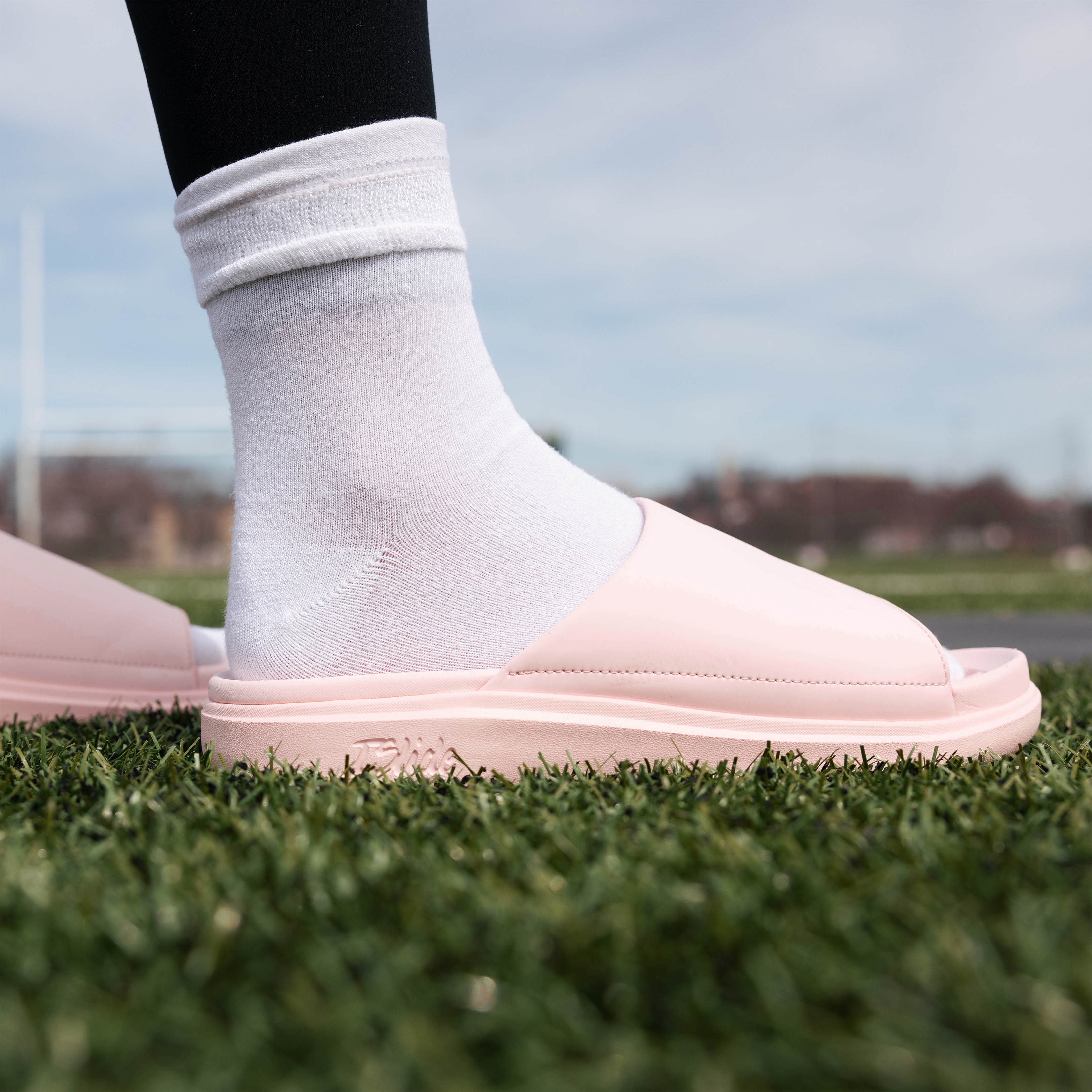 Collection of Person wearing light pink sandals and white socks on grass with a blurred background in a gallery layout