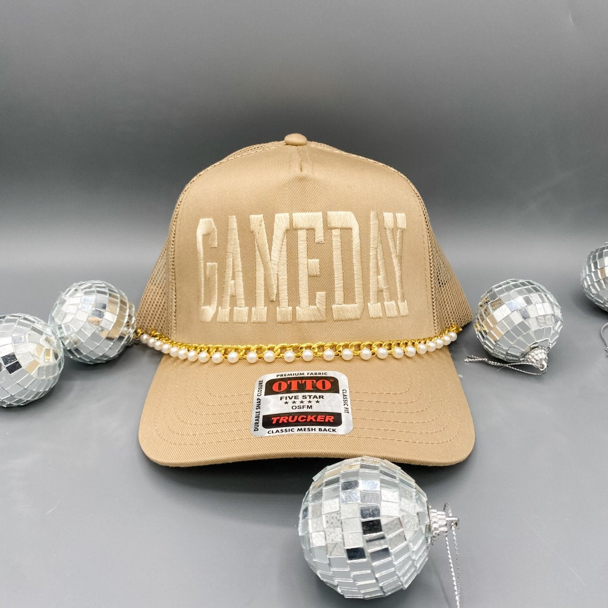 Collection of Beige cap with 'GAMEDAY' text and pearl embellishments on a gray background with disco balls. in a gallery layout